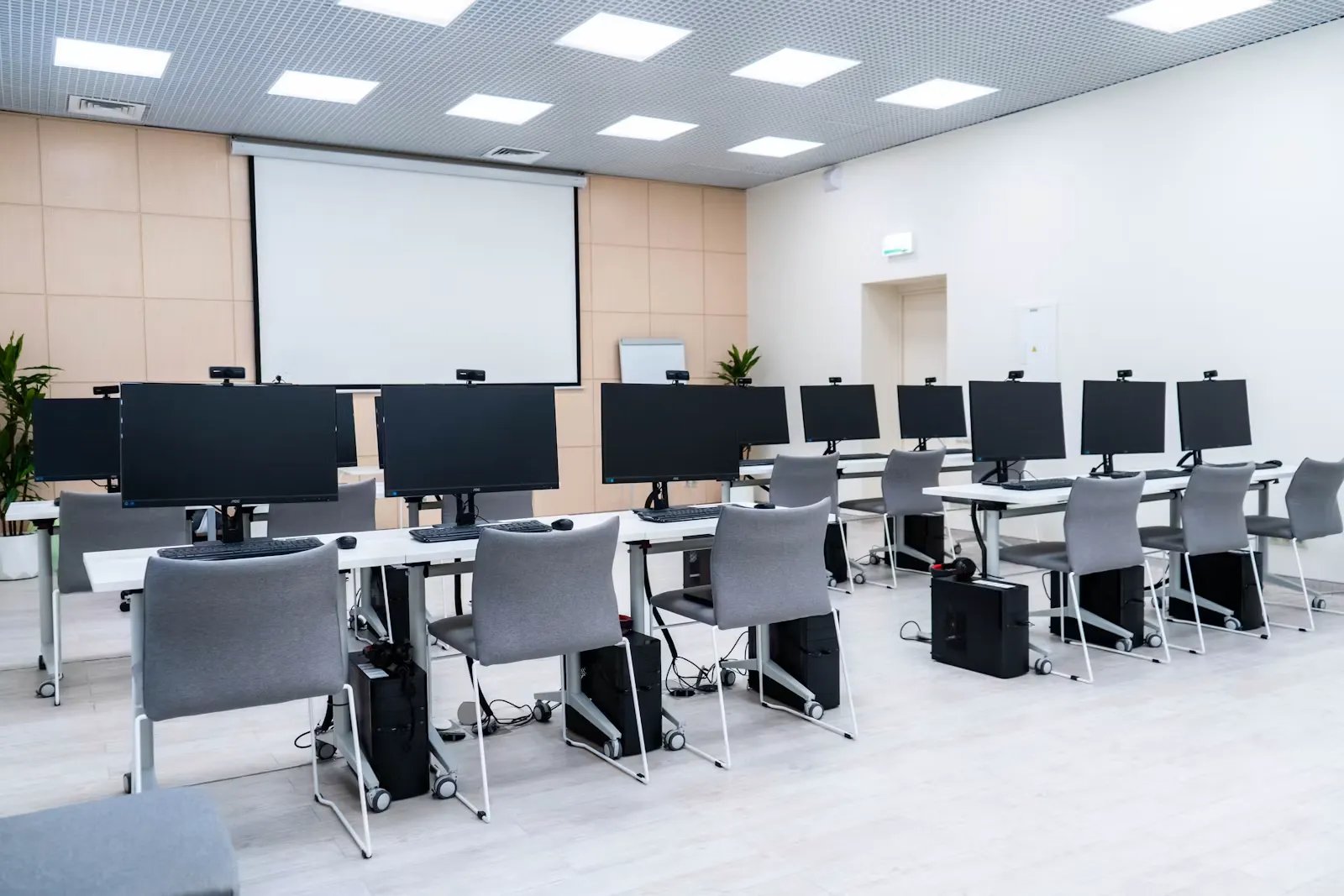 An angled view of a computer lab with monitors, keyboards and mice set out in rows on long white desks