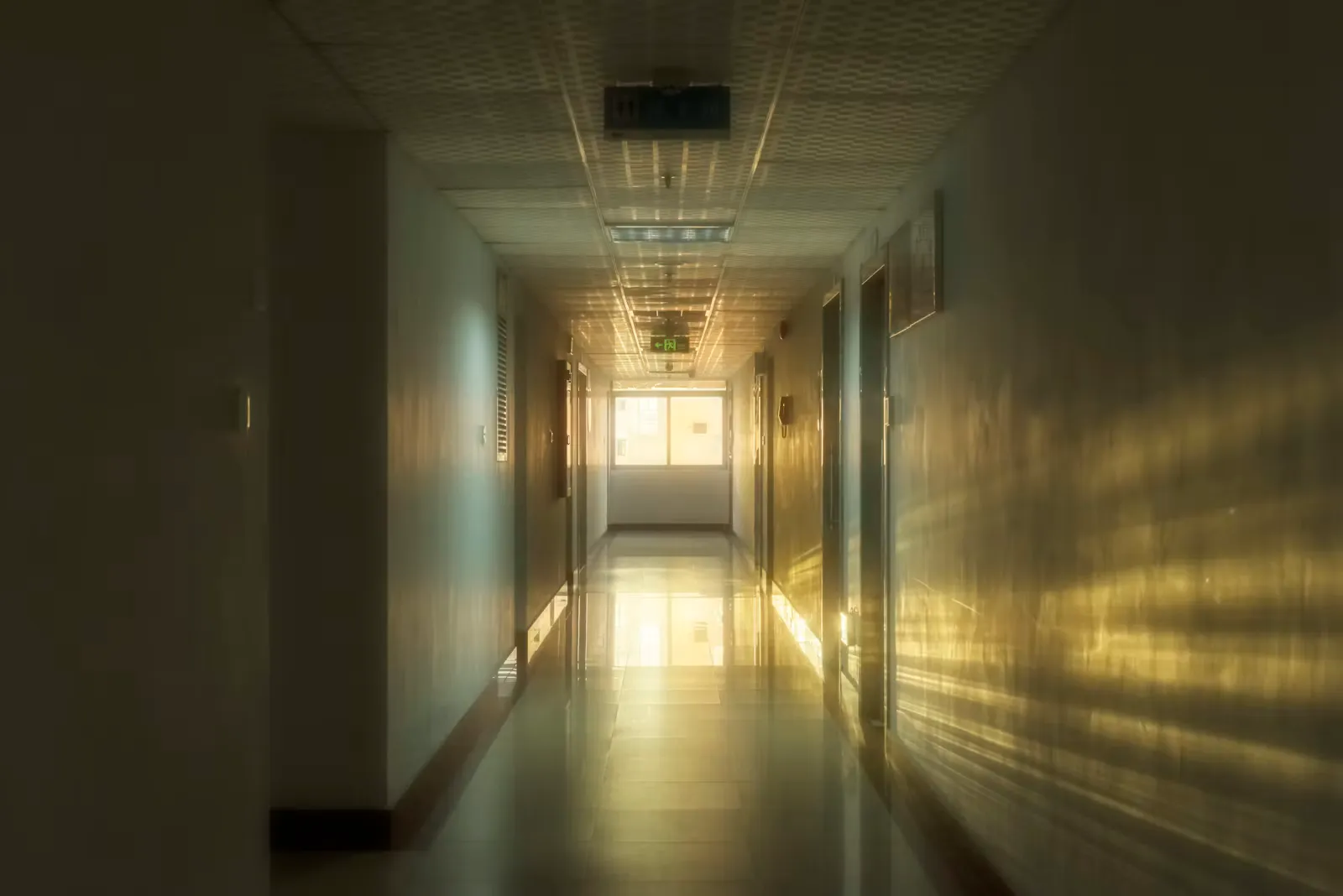 Empty white corridor with plain walls and bright overhead lighting, like the clinic hallways where newly registered doctors begin work in Europe