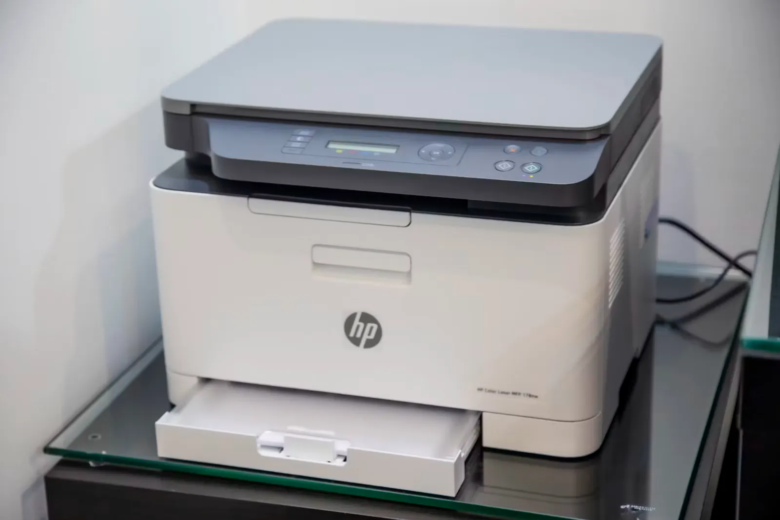 A home printer sitting on a desk in a small office, the kind used to print a NEET admit card before exam day