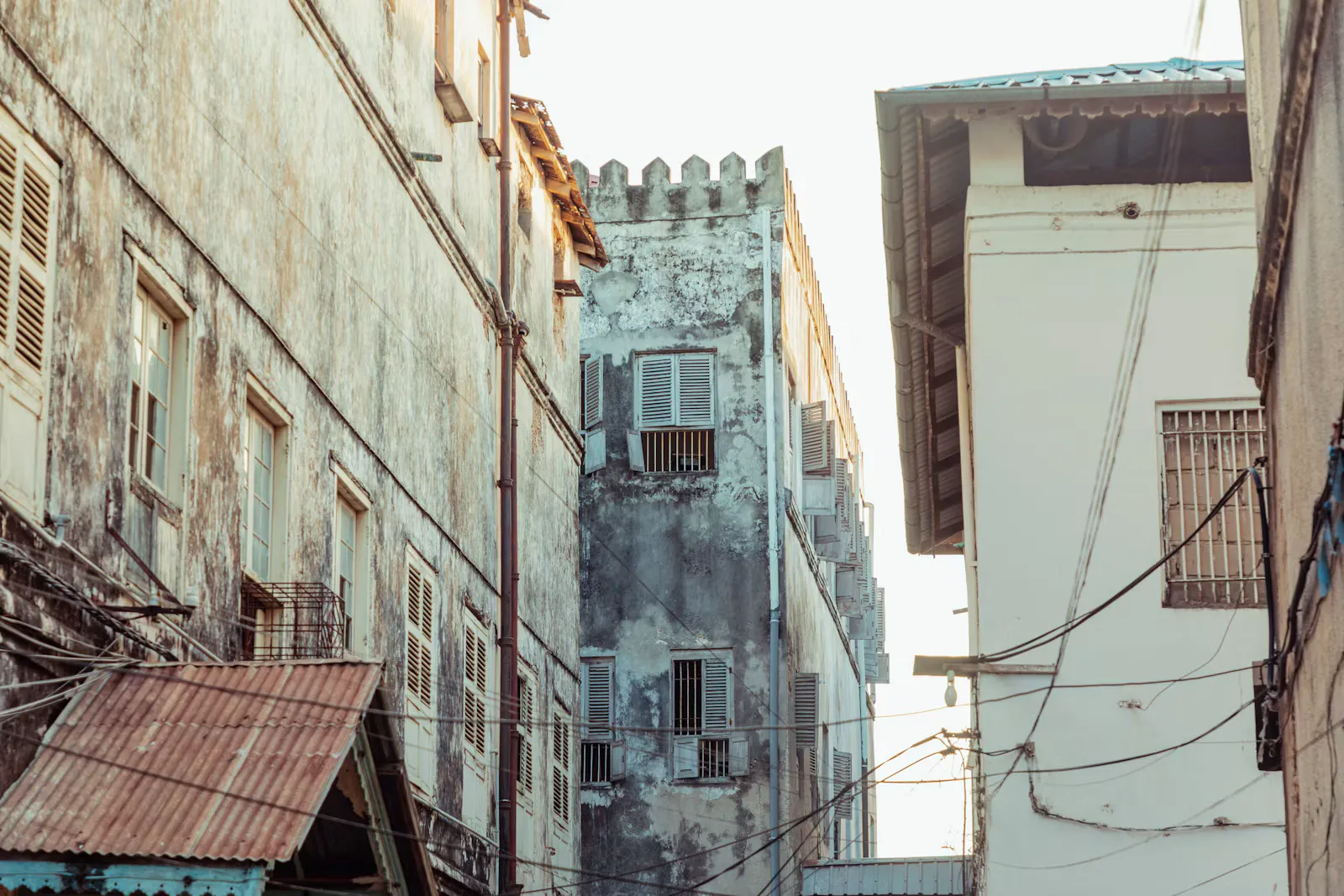 Enge Gasse in Stone Town auf Sansibar mit verwitterten Hausfassaden und Wellblechdach, Ziel vieler Praktika, für die die Route über die Gelbfieberimpfung entscheidet