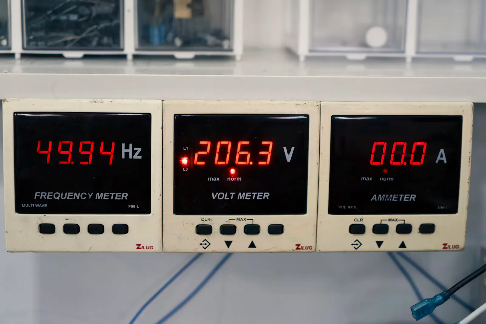 Three panel meters in a row showing a frequency of 49.94 Hz, a voltage of 206.3 V and a current of 0.00 A, a reminder that electrochemistry measures cell emf with no current drawn