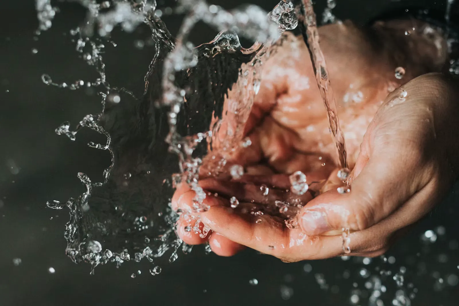 Zwei Hände fangen unter fließendem Wasser klare Wassertropfen auf, Symbolbild für Handhygiene im Auslandspraktikum