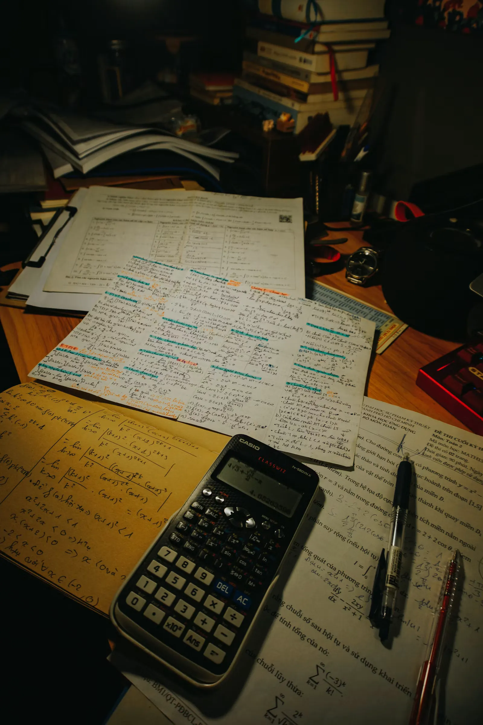 Desk with handwritten practice sheets, a calculator and pens