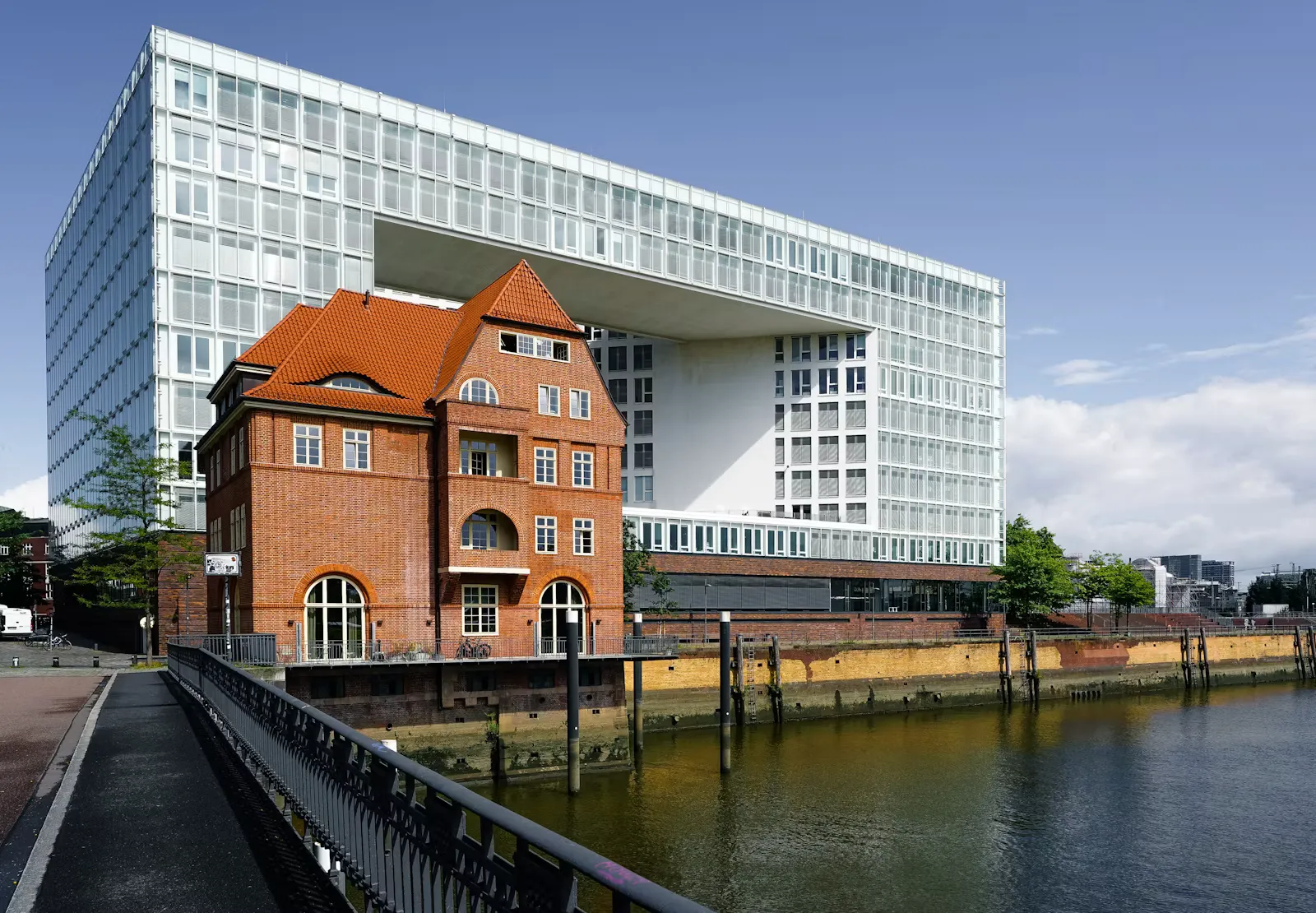 Moderner Glasbau und historisches Backsteinhaus am Wasser in der Hamburger HafenCity