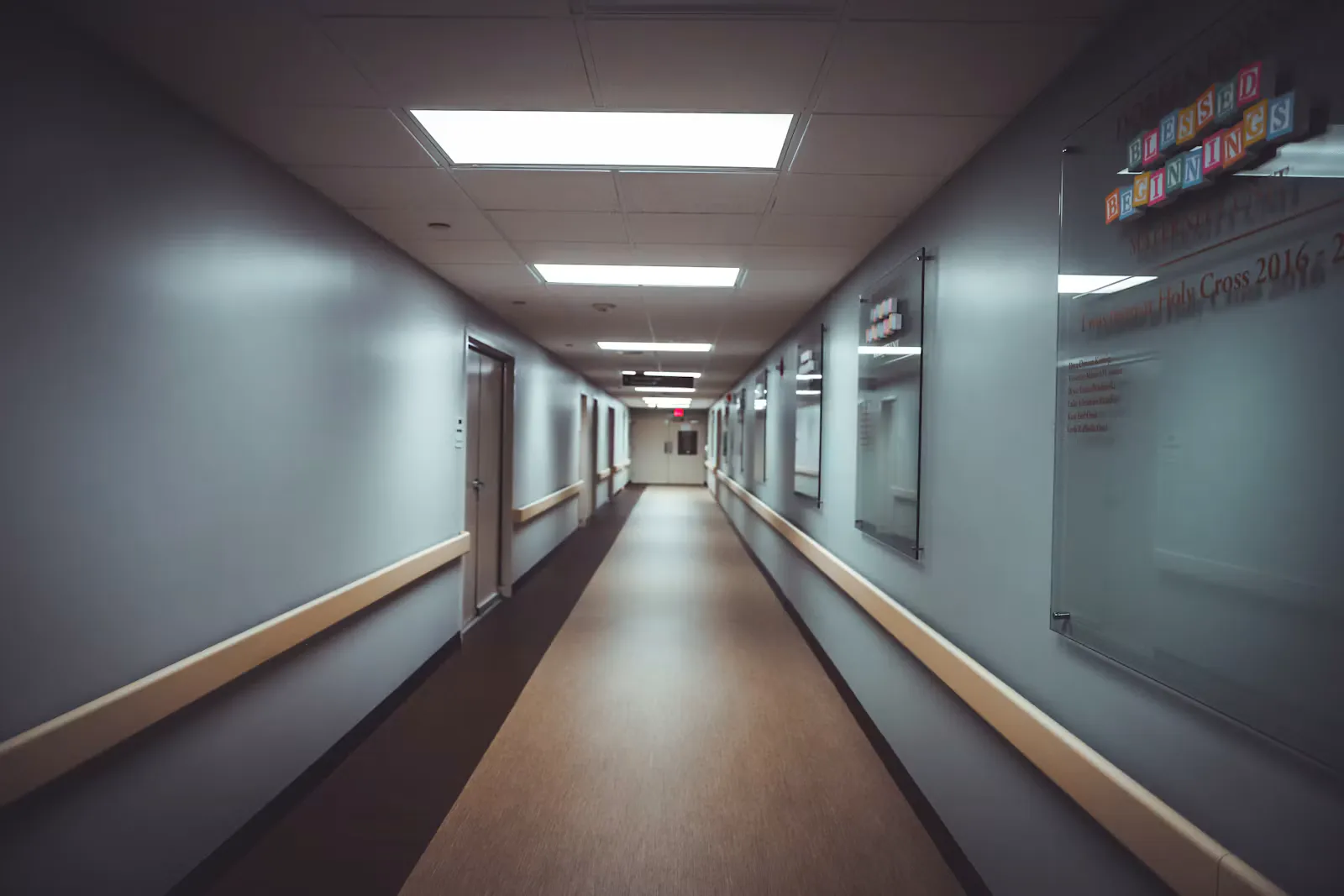 Leerer, hell beleuchteter Krankenhausflur mit Handläufen an beiden Wänden und Glastafeln, Sinnbild für den ersten Tag nach erfolgreicher Pflegepraktikum Bewerbung