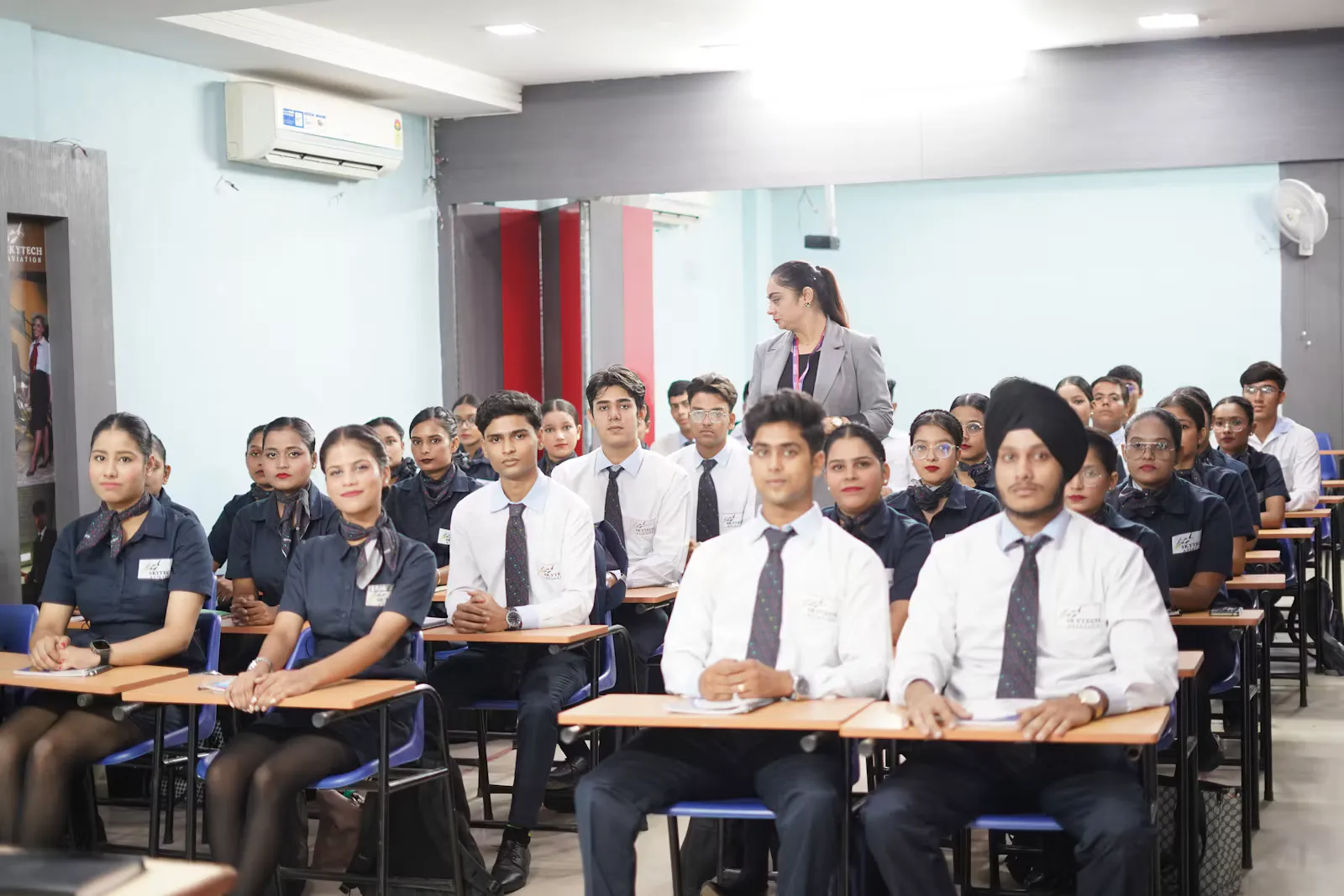 Indian students in uniform sitting at rows of desks in a bright classroom, the age group for whom the NEET full form becomes a daily phrase