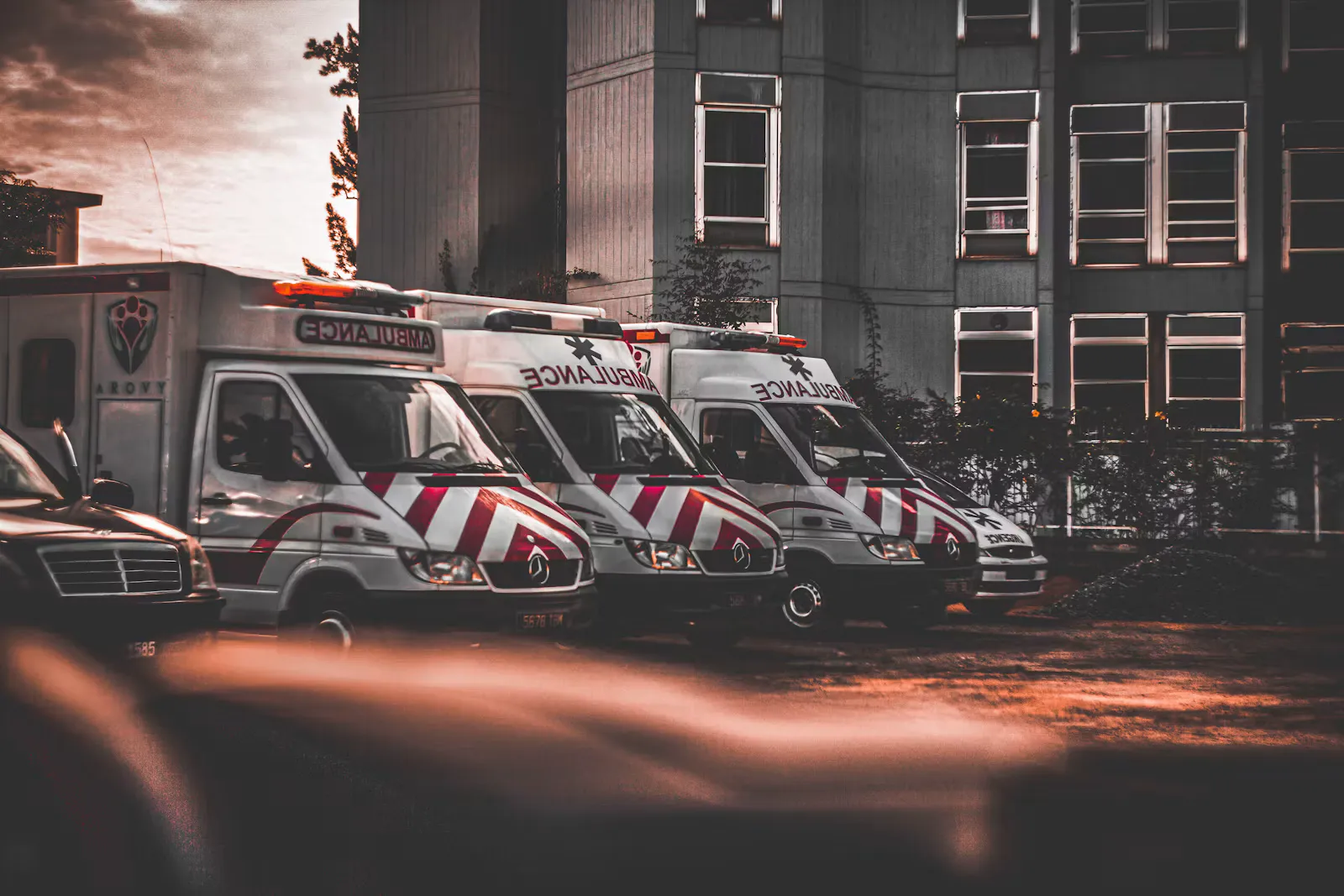 Mehrere Rettungswagen parken in einer Reihe vor einem mehrstöckigen Gebäude, Symbolbild für einen Freiwilligendienst im Rettungsdienst vor dem Medizinstudium