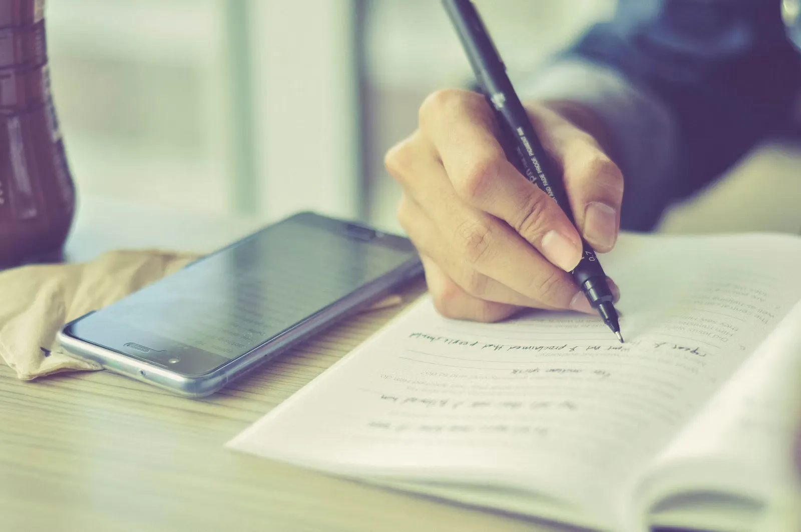 Person handwriting a cover letter with a pen on paper, representing drafting an application for a medical internship abroad