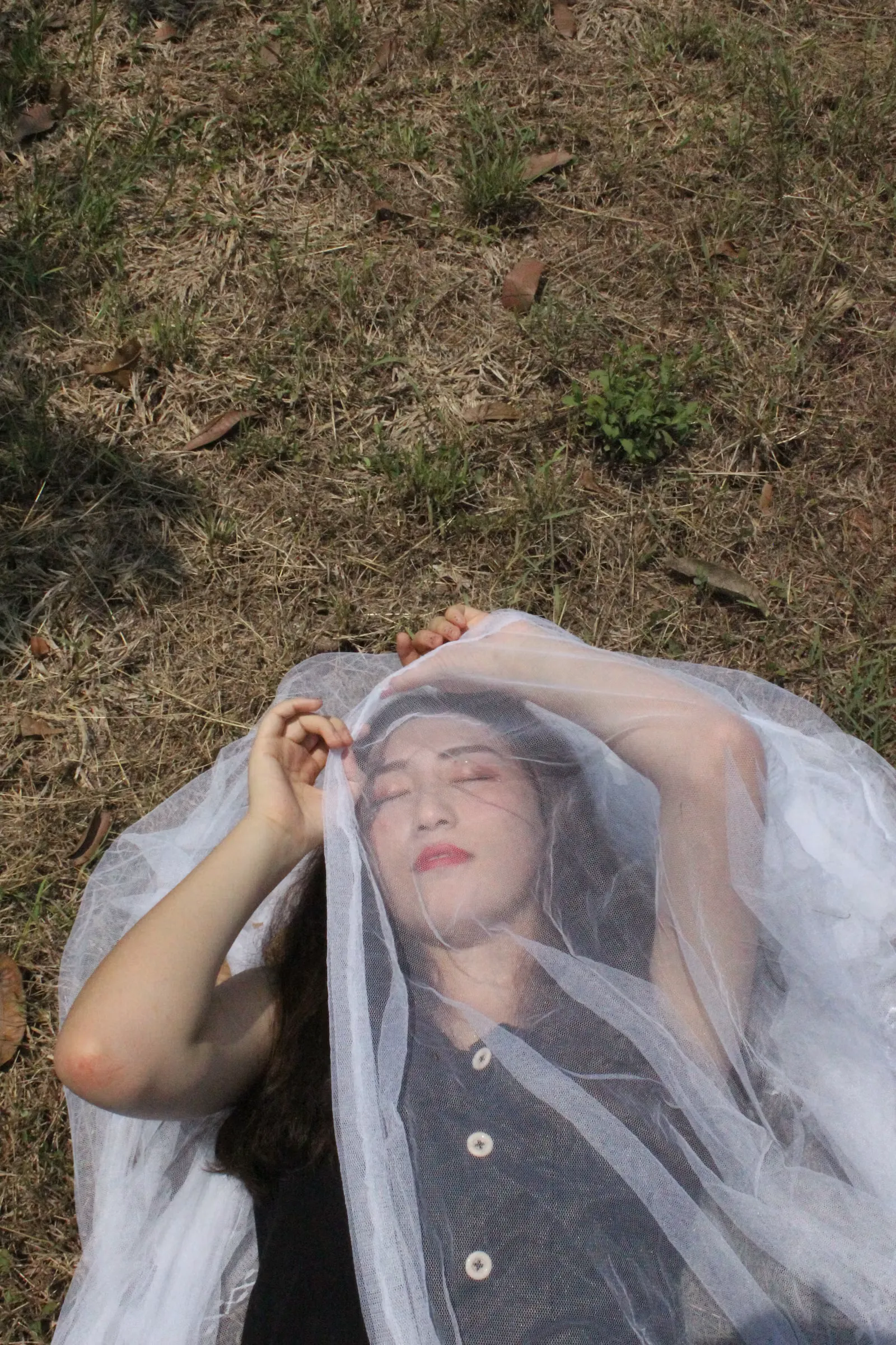 Fine white mesh netting draped over a person, a reminder that netting and covered skin are the low tech half of malaria protection