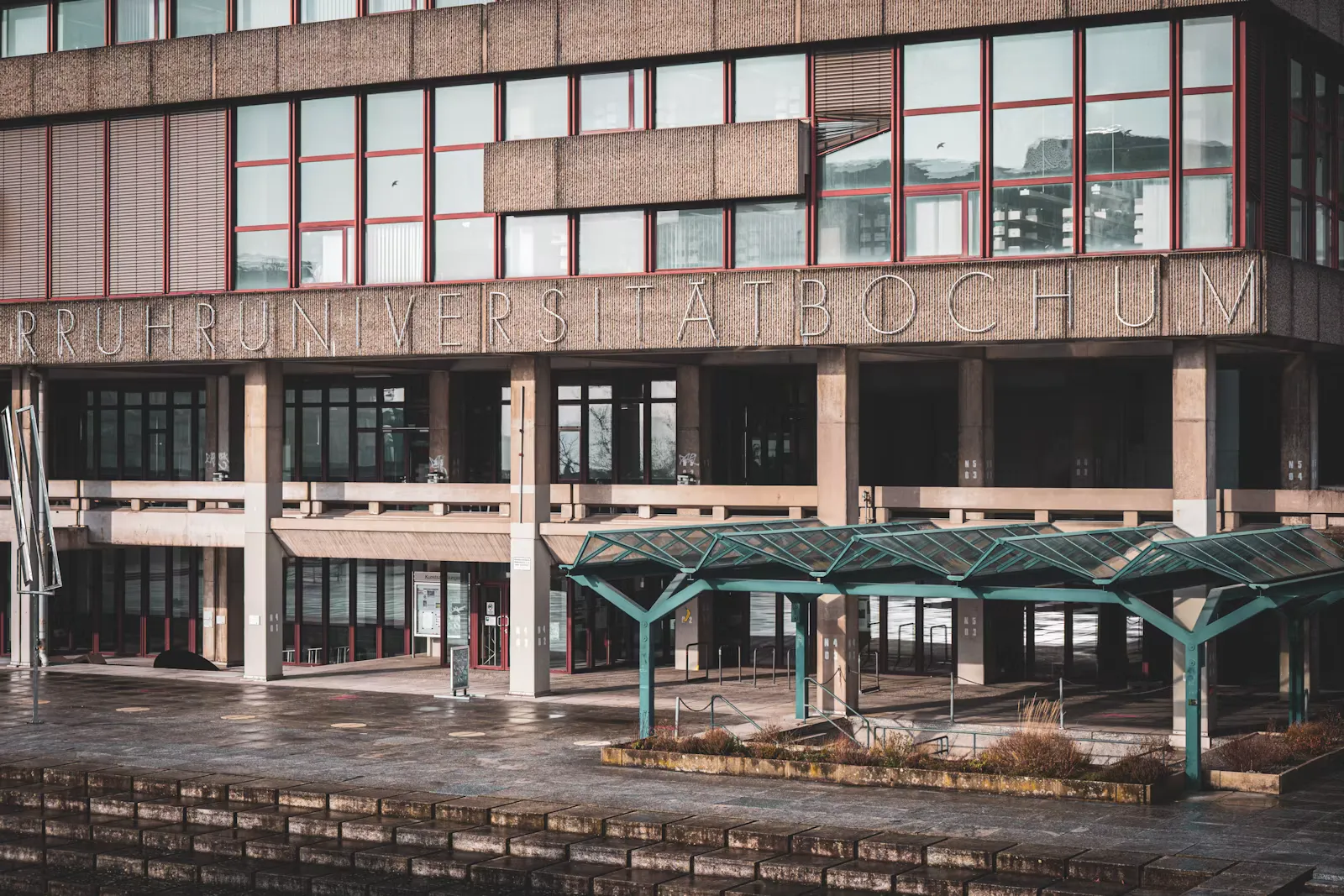 Modernes Universitätsgebäude mit großen Fensterfronten und einem Vordach über dem Eingang