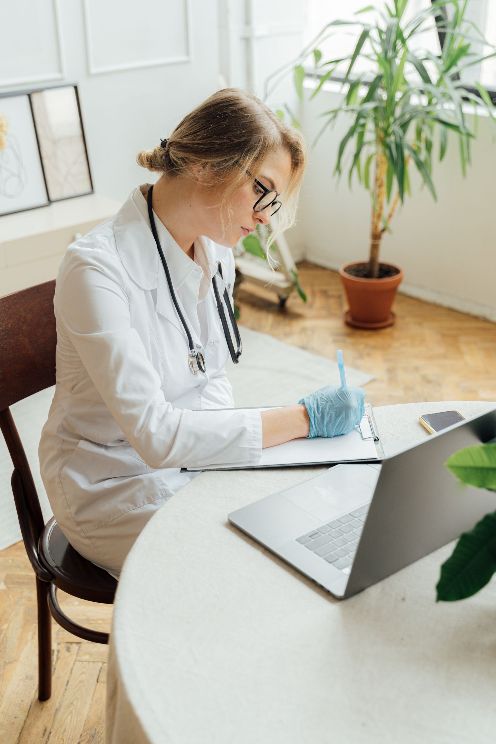 Healthcare professional writing on a clipboard at a desk, representing the written request needed to secure paid educational leave abroad