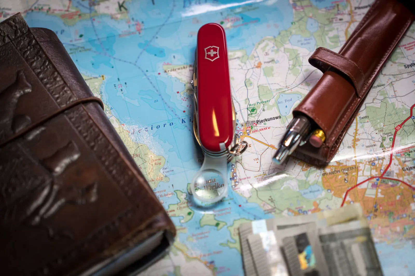 Landkarte auf einem Tisch, darauf ein Stift, ein Portemonnaie und ein Taschenmesser, Sinnbild fuer die Reiseplanung rund um die Diensttage