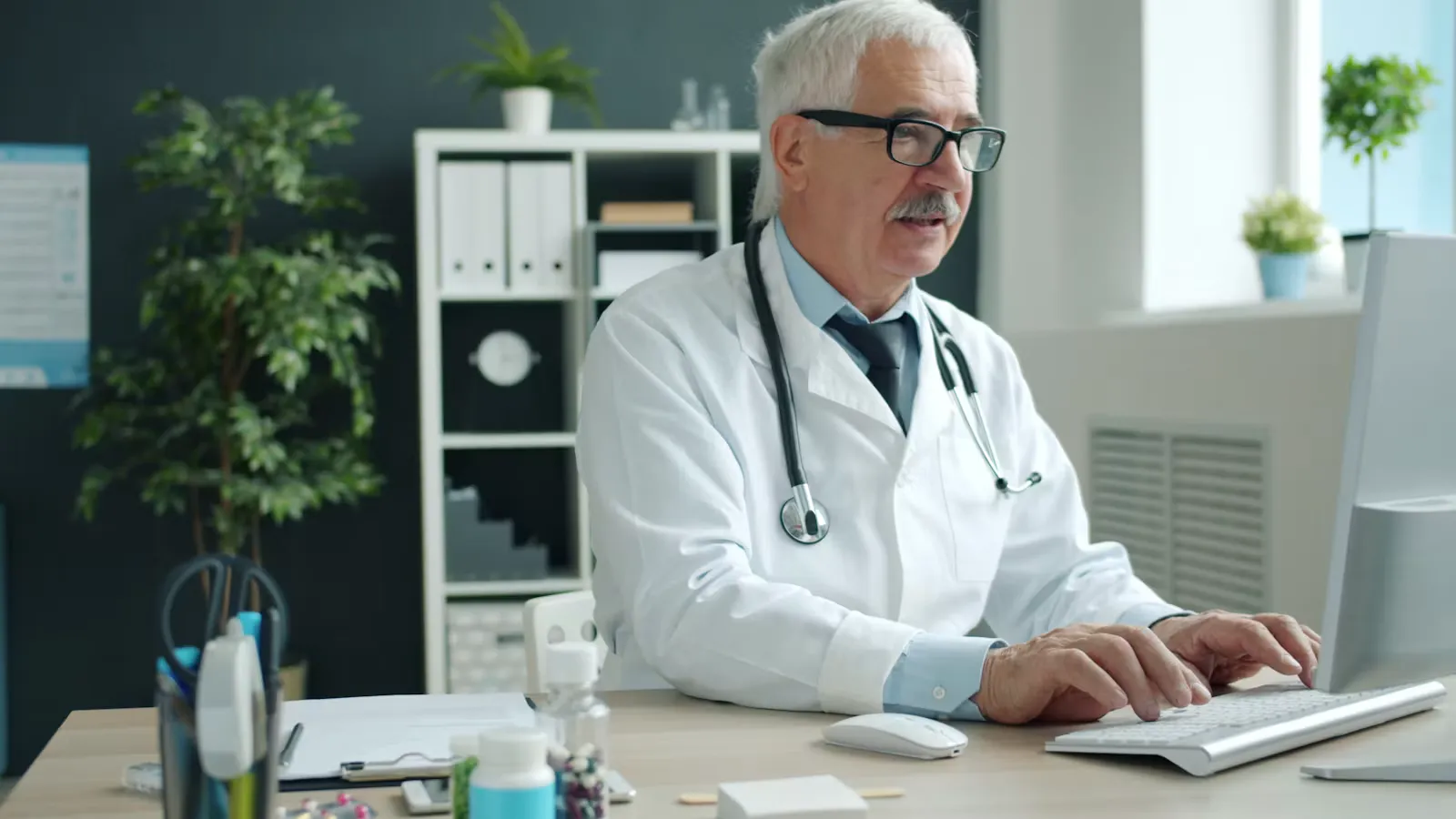 A doctor typing on a computer in an office